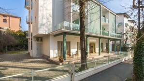A hotel with a modern design, featuring a glass facade, outdoor seating area, and a well-maintained garden. - Hotel Zamagna (Cesenatico)