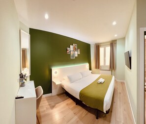 A hotel room with a bed, bedside table, and a desk with a chair. - Hostal Sol Square Madrid (Madrid)