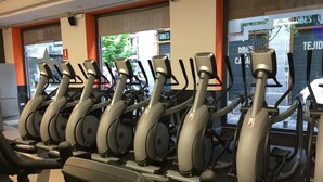 A row of stationary bikes in a gym with a view of the street outside. - Hostal Sol Square Madrid (Madrid)