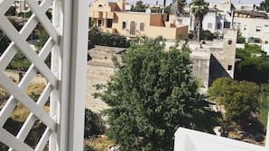 Un balcon orné d’une pancarte « Détendez-vous », donnant sur un quartier résidentiel avec différents immeubles et de nombreux espaces verts.