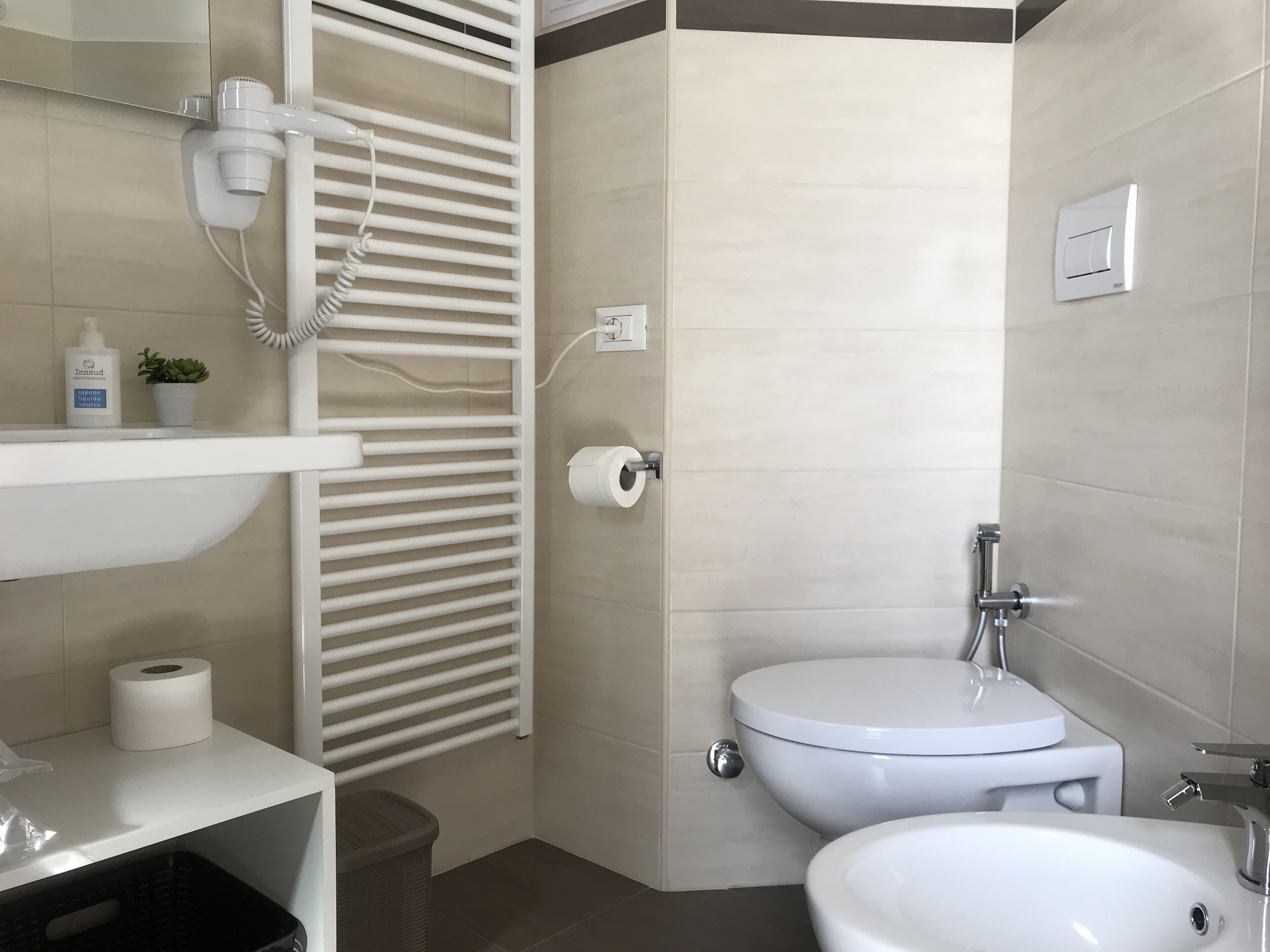 Un baño moderno con inodoro, lavamanos y toallero integrado.
