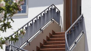 Un escalier avec des rampes en métal et des marches en bois menant à une porte.