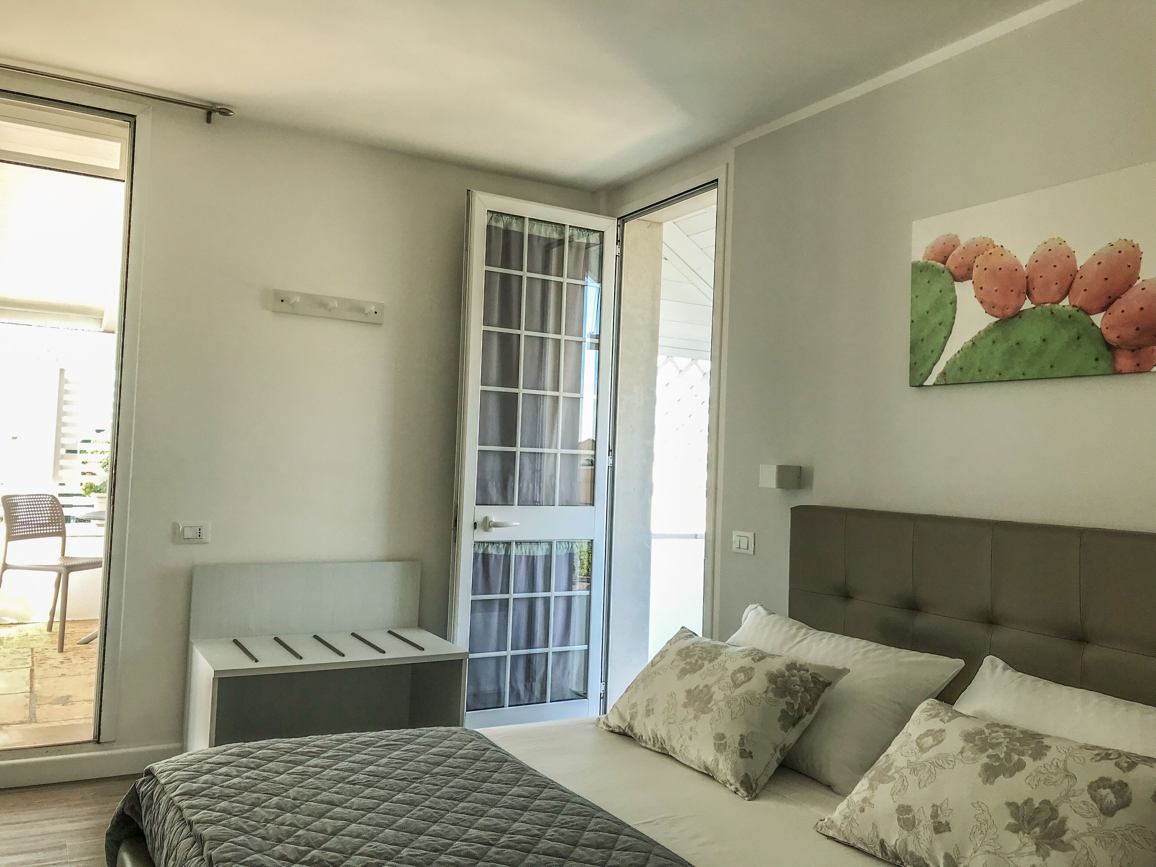 Un dormitorio con cama, mesita de noche, puerta y ventana.