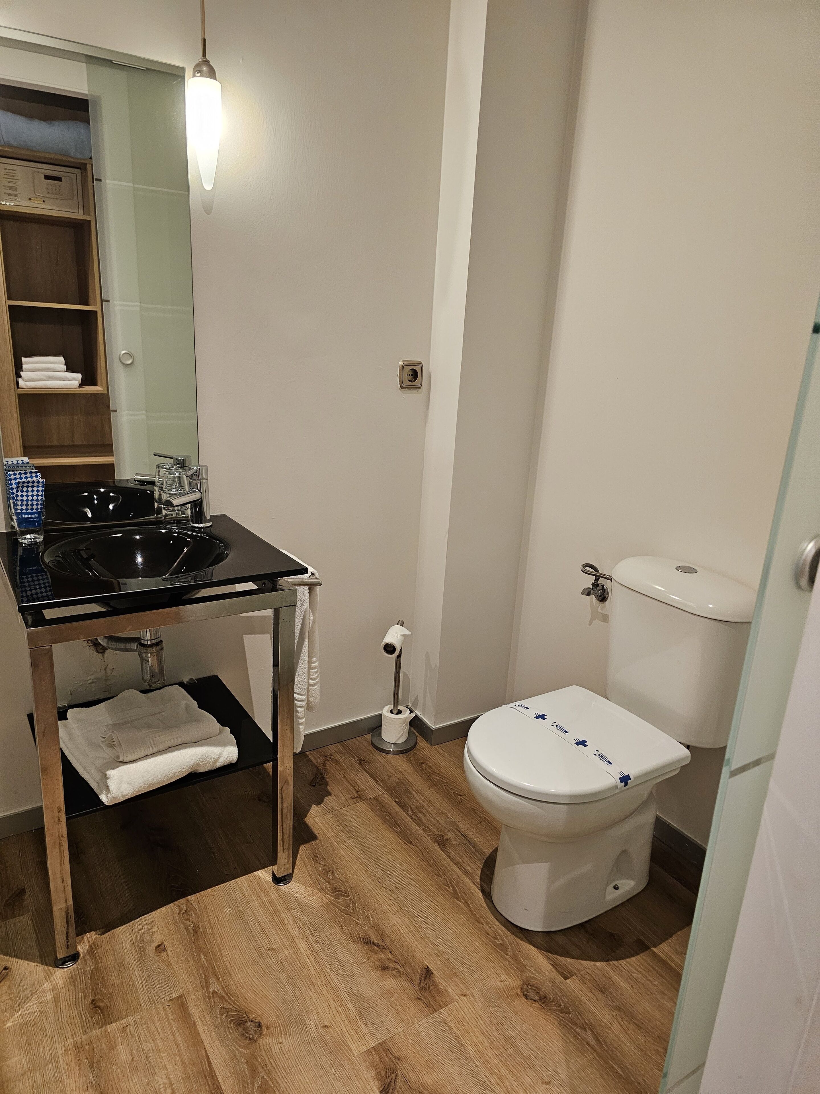 A bathroom with a black sink, a toilet, and a mirror.