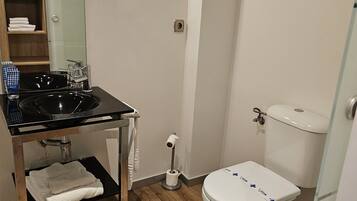 A bathroom with a black sink, a toilet, and a mirror.