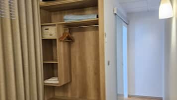 Habitación de hotel con un armario de madera, un televisor encima, un equipo de aire acondicionado, una mesa y una silla.