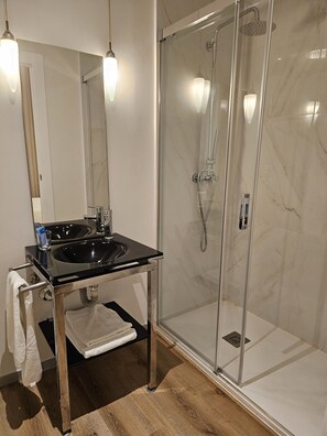 Tweepersoonskamer | Badkamer | Een douche, een haardroger, handdoeken, zeep