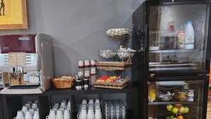 A coffee machine, baskets, cups, and a refrigerator with food items.