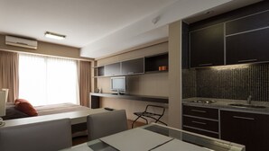 Moderni hotellihuone, jossa on ruokailutila, televisio ja pieni keittiö.