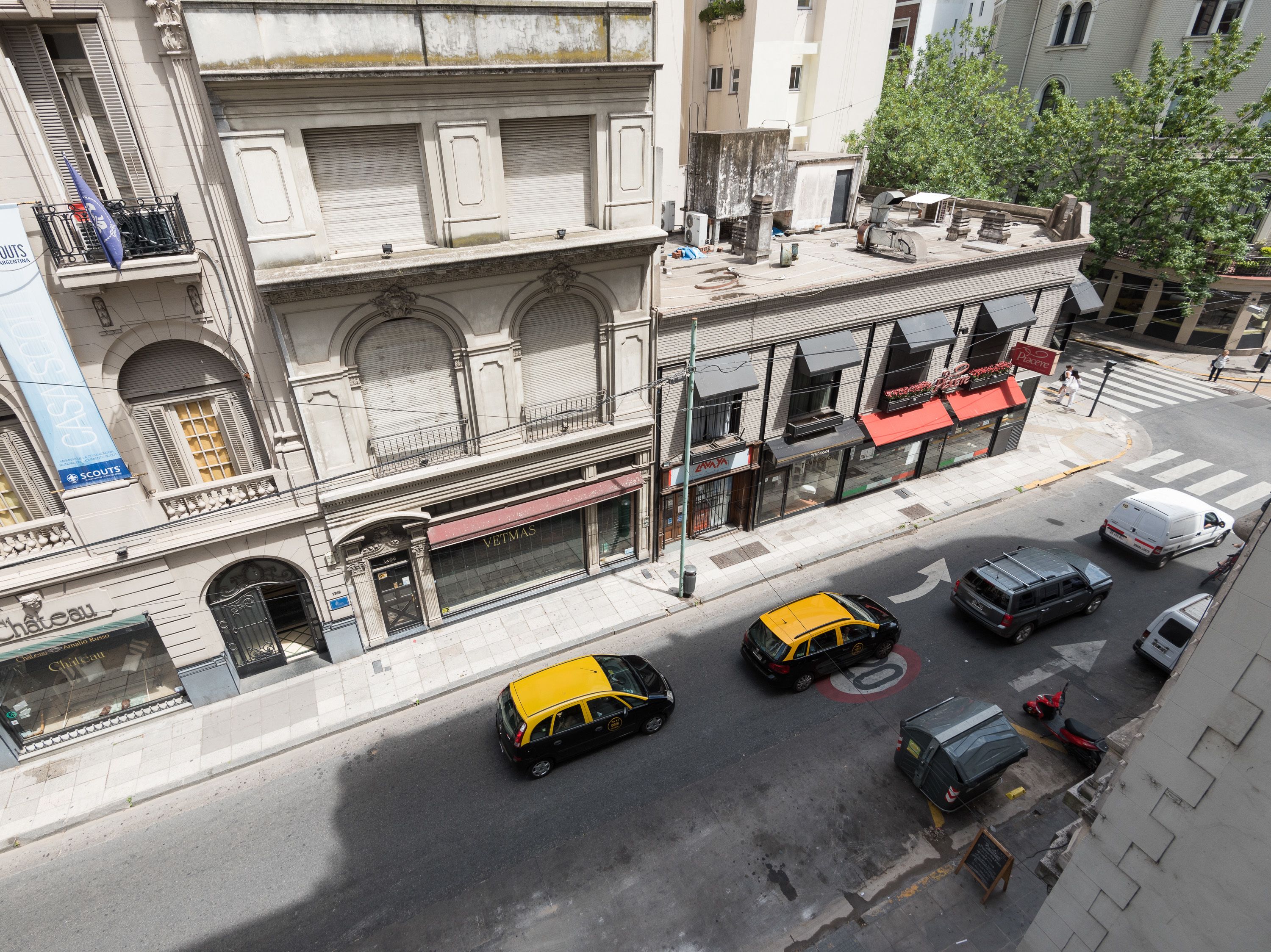 Un edificio de varios pisos con fachada antigua, un toldo rojo y un escaparate visible con un letrero.