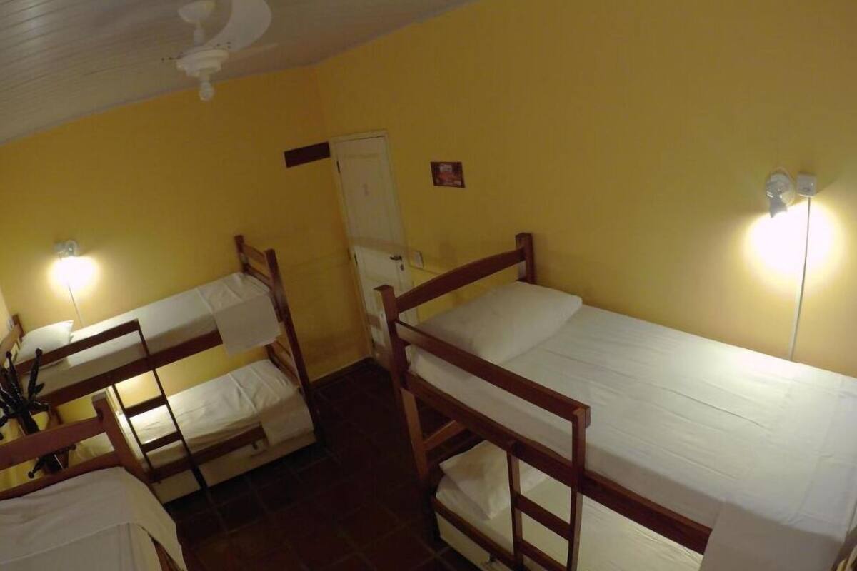 Une chambre de dortoir avec deux lits superposés, un ventilateur de plafond et une porte.
