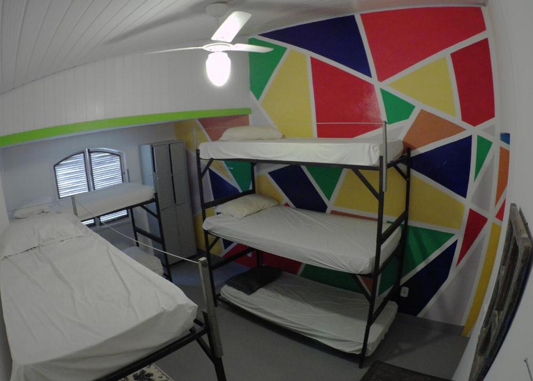 A bunk room with a bed, a desk, and a ceiling fan.