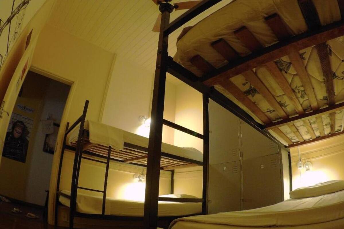 Une chambre de dortoir avec des lits superposés, un plafond en bois et une porte donnant sur une autre pièce.