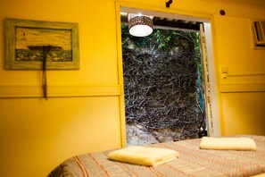A room with yellow walls, a bed with a striped bedspread, and a framed picture on the wall.