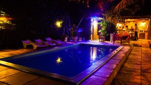 Una piscina con sillas de descanso, zona de bar y área de estar cubierta.