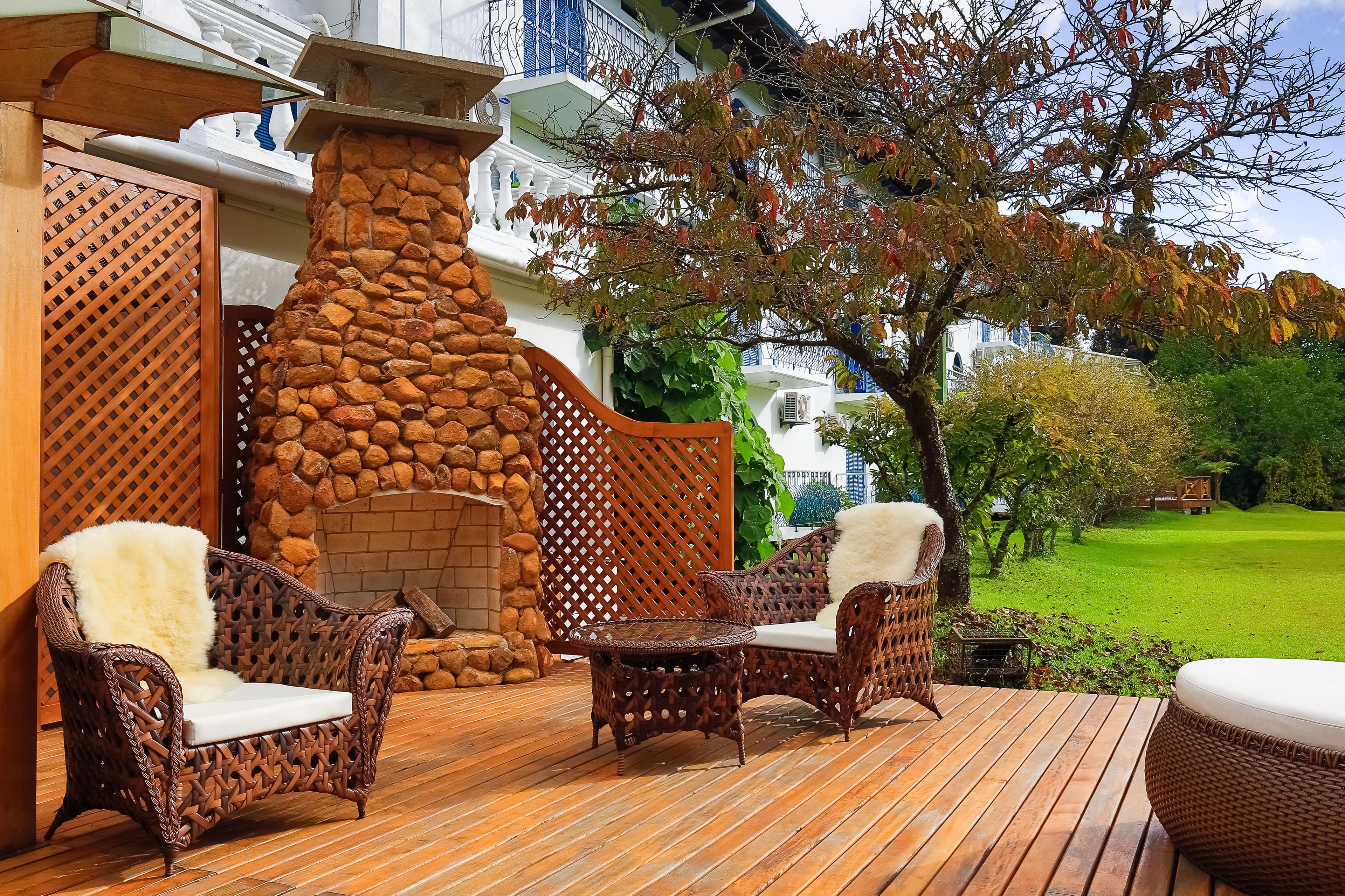 Eine Holzterrasse mit Korbmöbeln und einem Steinkamin.
