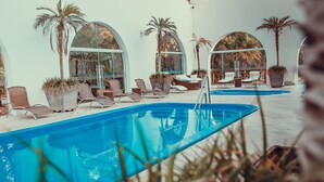 A pool area with lounge chairs and potted plants.