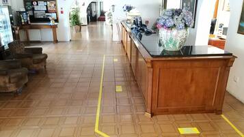 Un hall de hotel con una larga recepción, una máquina de café y un área de descanso con sillones.