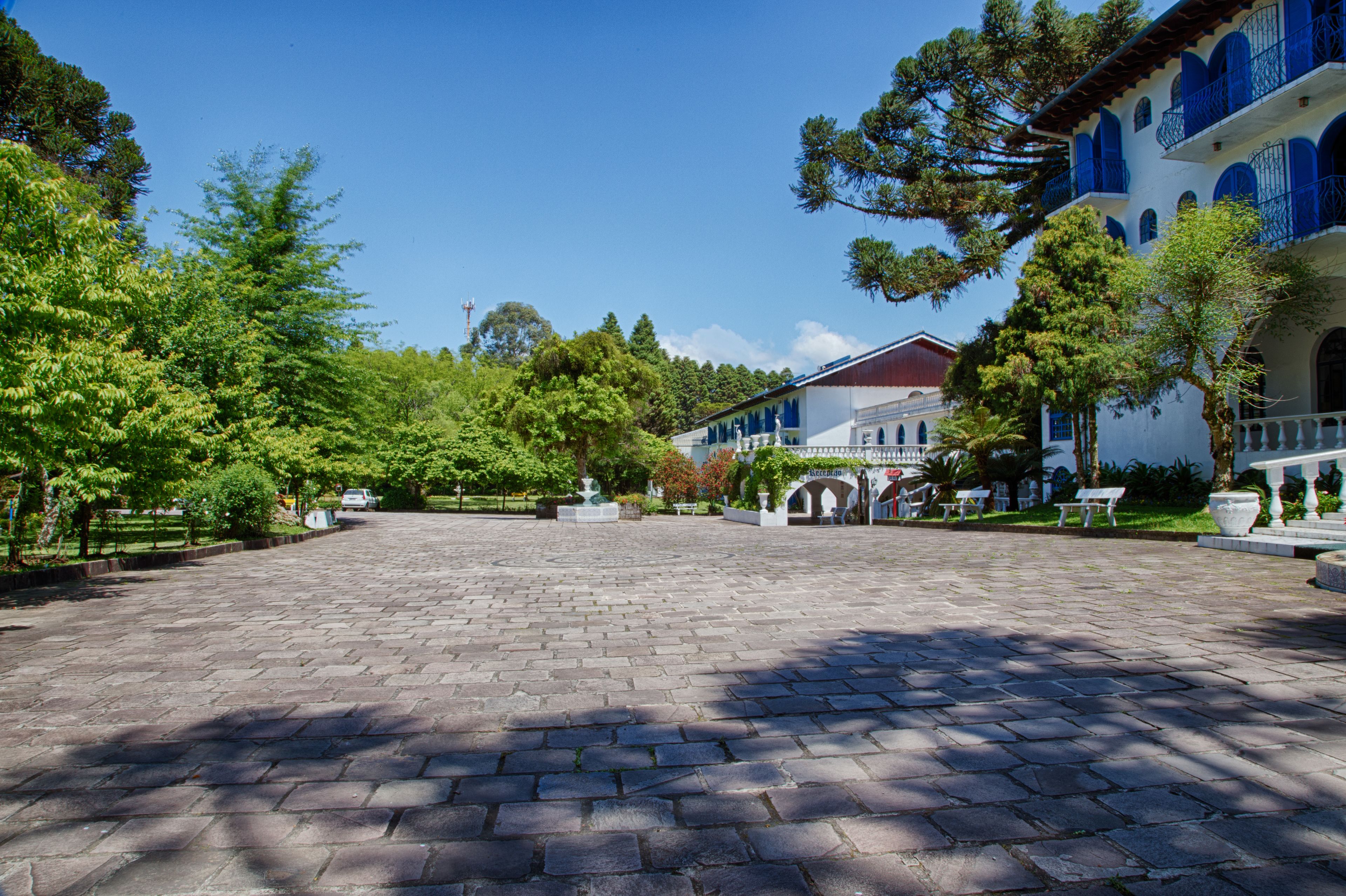A paved courtyard with a fountain, surrounded by trees and buildings with blue balconies.