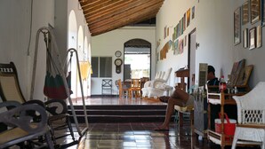A room with a wooden ceiling, a bed, a chair, a table, and a wall with pictures. - El Arca de Noé Lodging (Granada)