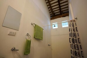 A bathroom with a shower curtain, a towel rack with two towels, a mirror, and a light switch. - El Arca de Noé Lodging (Granada)
