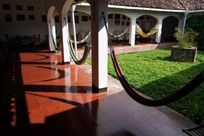 A covered outdoor area with tiled flooring, hammocks, and a grassy lawn. - El Arca de Noé Lodging (Granada)