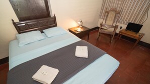 A neatly made bed with pillows and a folded towel, a bedside lamp, a chair, and a small table with a laptop. - El Arca de Noé Lodging (Granada)