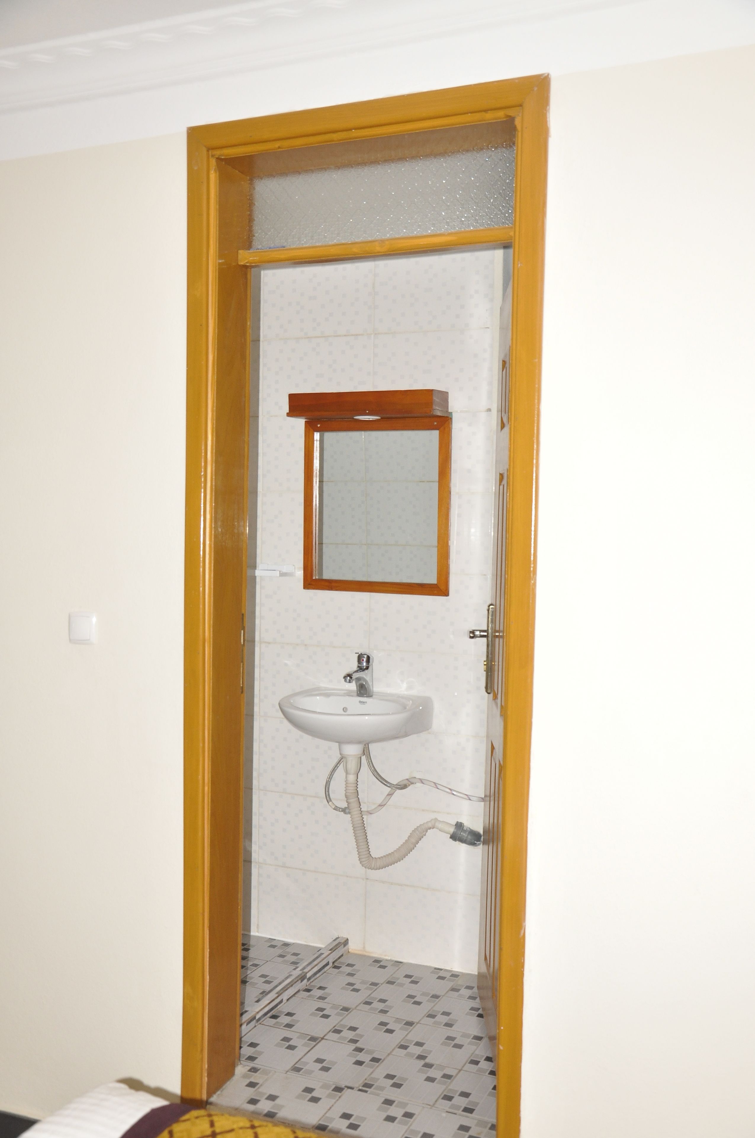 A bathroom with a wooden door, a white sink, and a mirror.