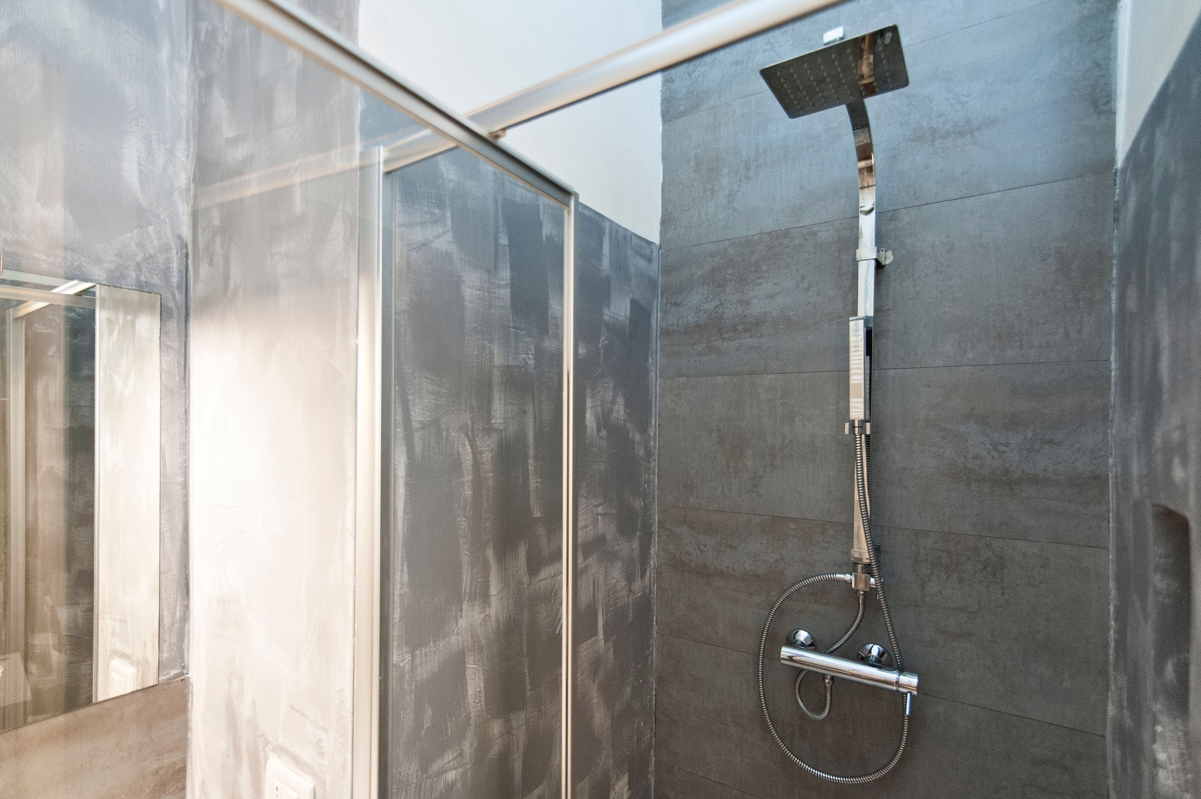 A modern shower with a handheld showerhead and a wall-mounted control panel.