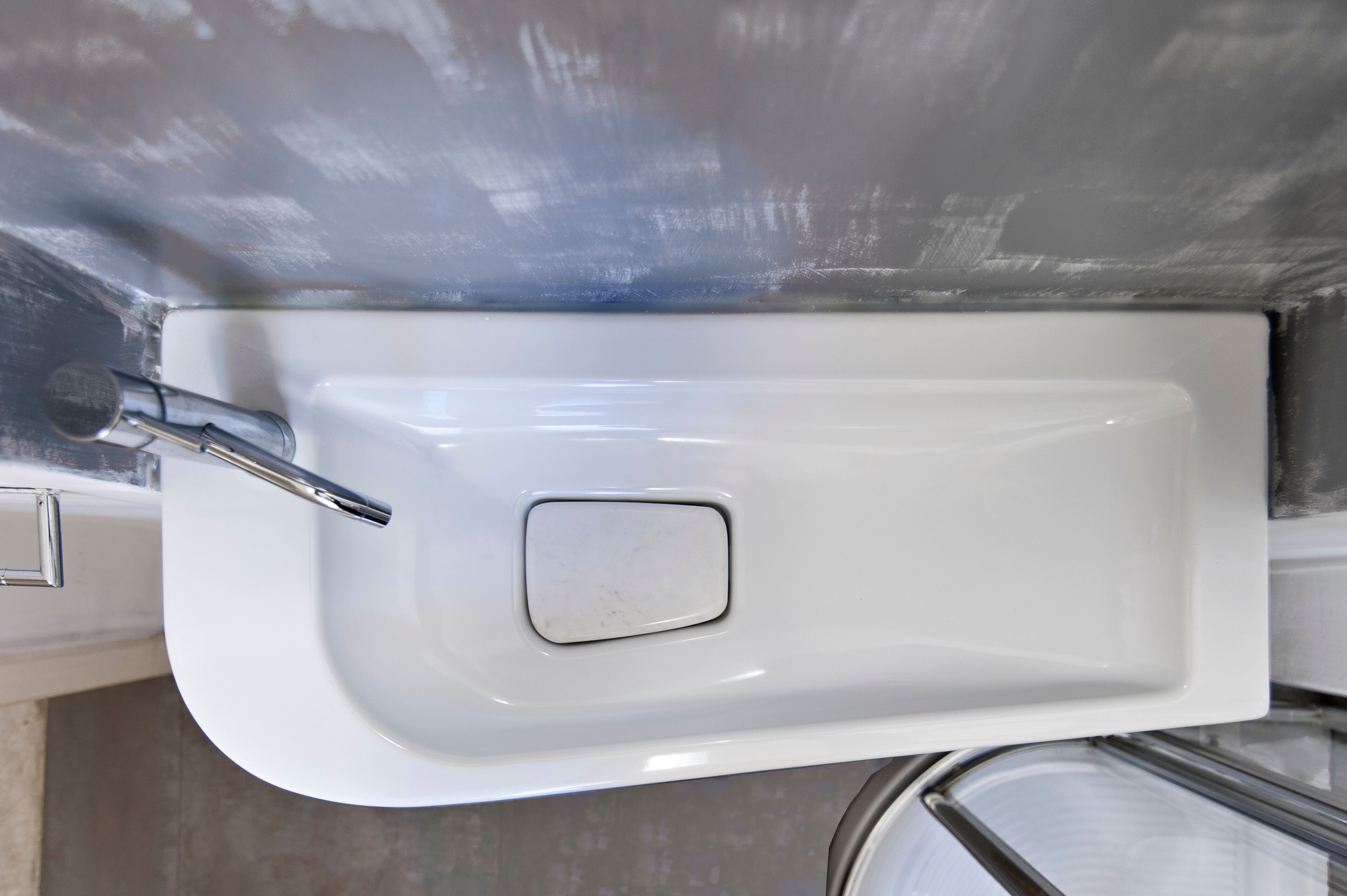 Un lavamanos blanco rectangular con un grifo cromado y un jabonera cuadrada.