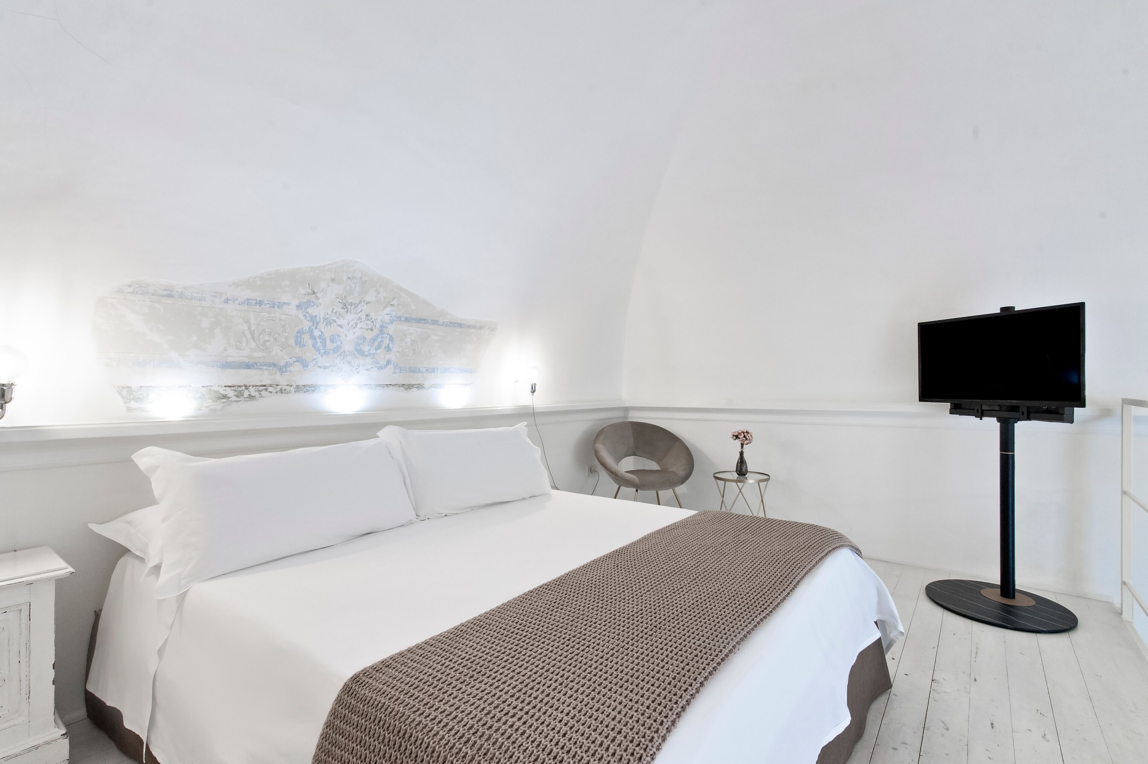 Une chambre d’hôtel avec un grand lit, un téléviseur à écran plat, une petite table et une chaise.