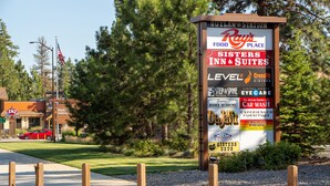A signboard with various business advertisements including a food place, a hotel, and other services. - Sisters Inn And Suites (Sisters)