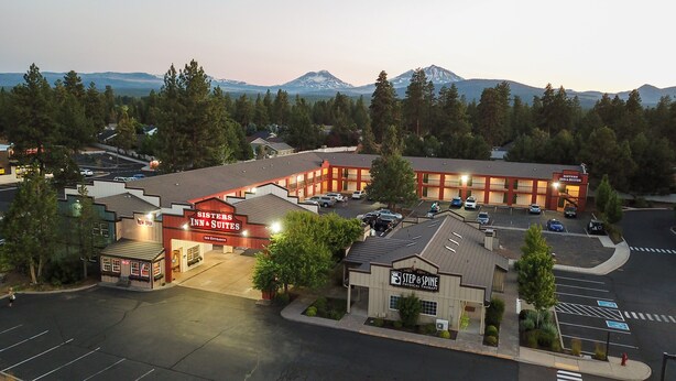 A motel with a sign reading "Sisters Inn & Suites" and a physical therapy center named "Step & Spine." - Sisters Inn And Suites (Sisters)