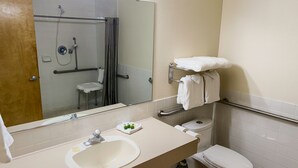 A bathroom with a sink, toilet, and shower. There are towels on a rack and a mirror above the sink. - Sisters Inn And Suites (Sisters)