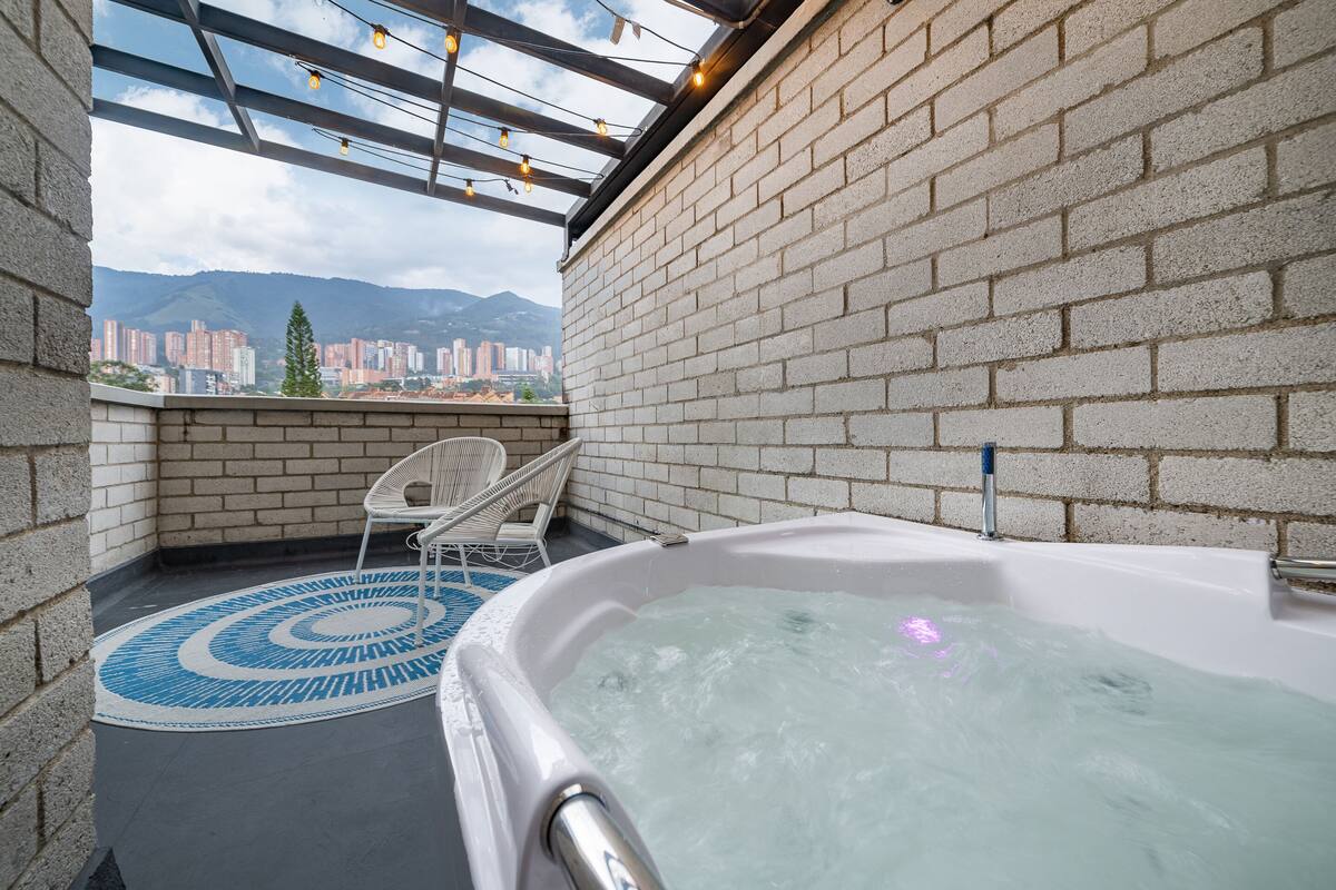 En tagterrasse med jacuzzi, udsigt over bybilledet og en murstensmur.