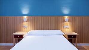 Een hotelkamer met een bed, twee nachtkastjes en een houten paneelwand.