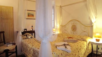 Ein Schlafzimmer mit einem Himmelbett, einem Nachttisch mit Lampe und einem Sessel.