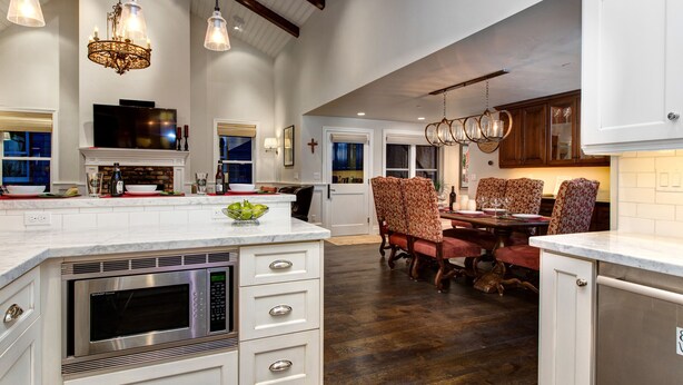 A spacious kitchen with a large island, built-in microwave, and elegant pendant lighting.