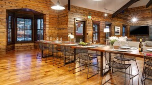 A wooden-paneled room with a long dining table, chairs, and a television.