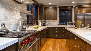 A modern kitchen with stainless steel appliances, wooden cabinets, and a marble countertop.