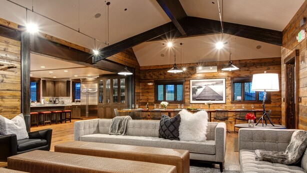 A spacious living area with a large sofa set, a dining table, and a kitchen in the background.