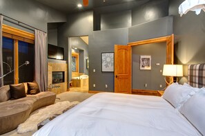 Ett modernt hotellrum med en stor säng, en soffa, ett badrum med handfat och spegel samt en tv som är monterad på väggen.