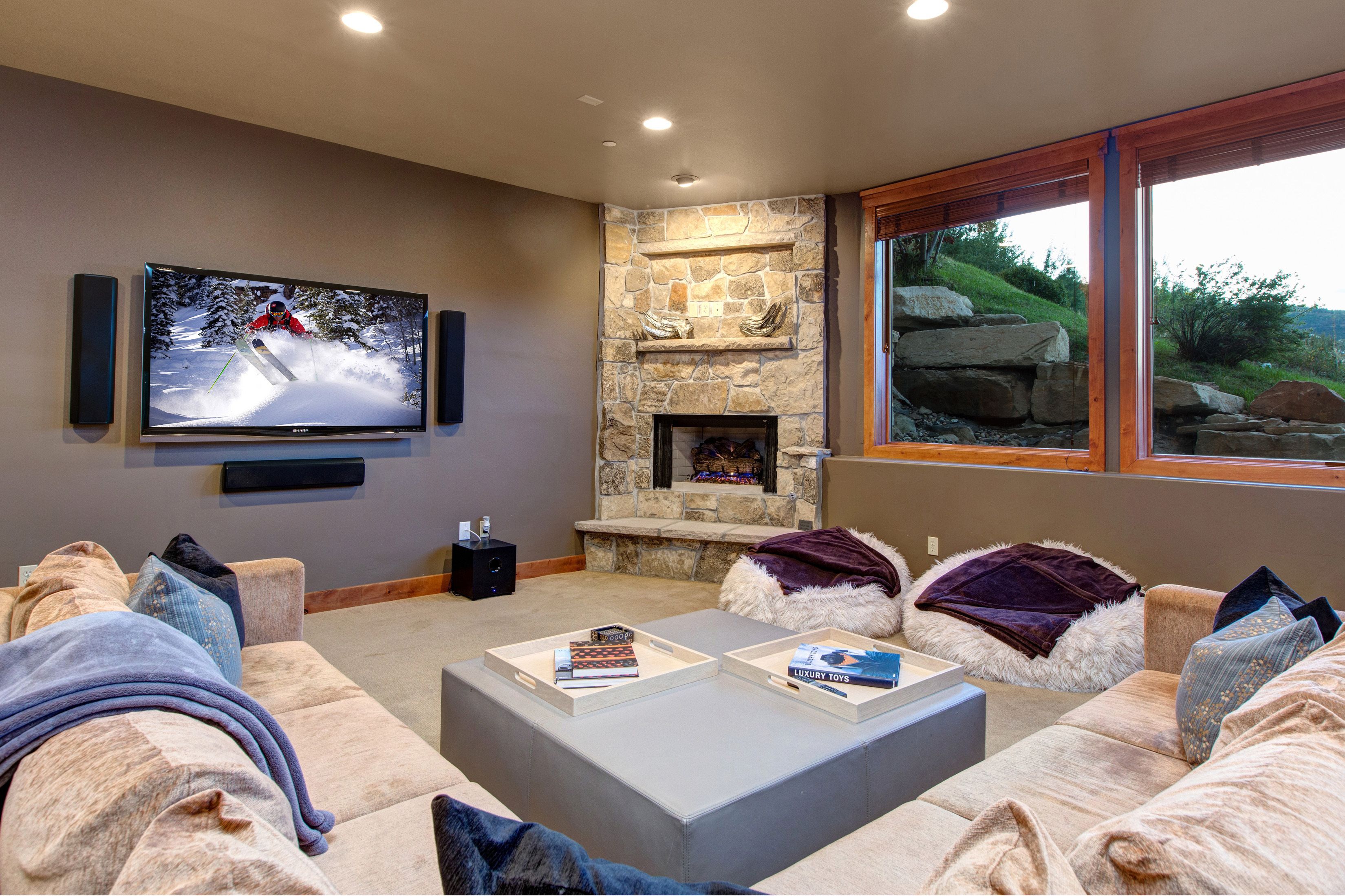 Una sala de estar moderna con una chimenea de piedra, un televisor de pantalla plana grande y un rincón de estar acogedor con sofás cómodos y una mesa de centro.