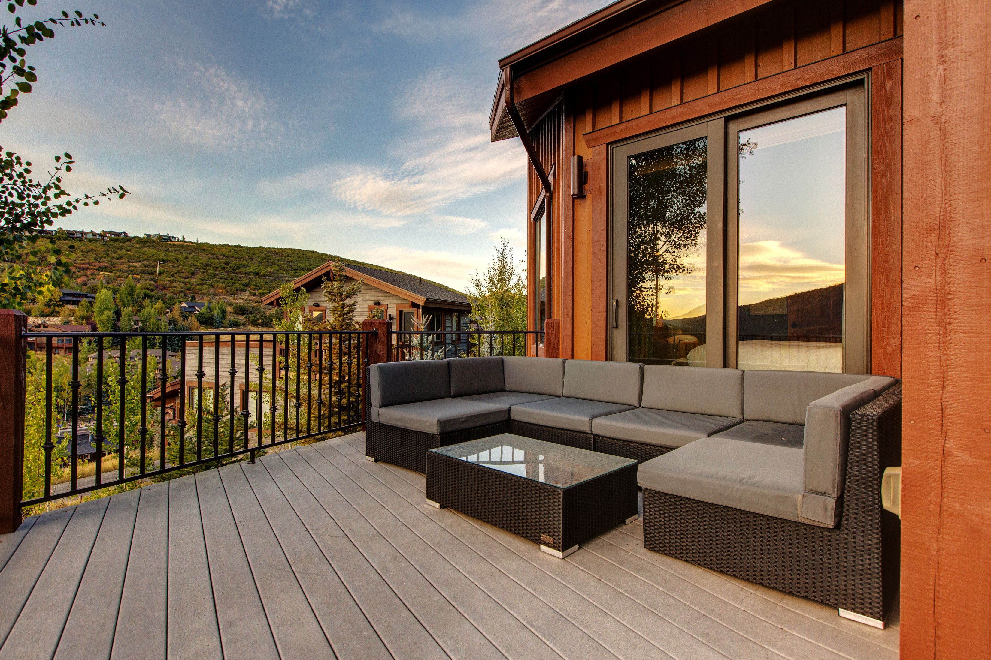 Une terrasse en bois avec un canapé modulable et une table basse en verre.