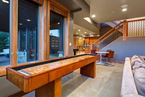 Relax in a spacious living area with a shuffleboard table and comfortable sofa, perfect for socializing.