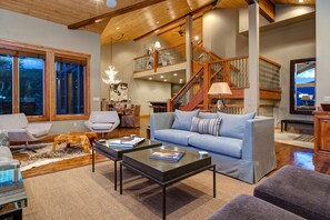 A spacious living room with a large sofa, a coffee table, and a staircase leading to an upper level.