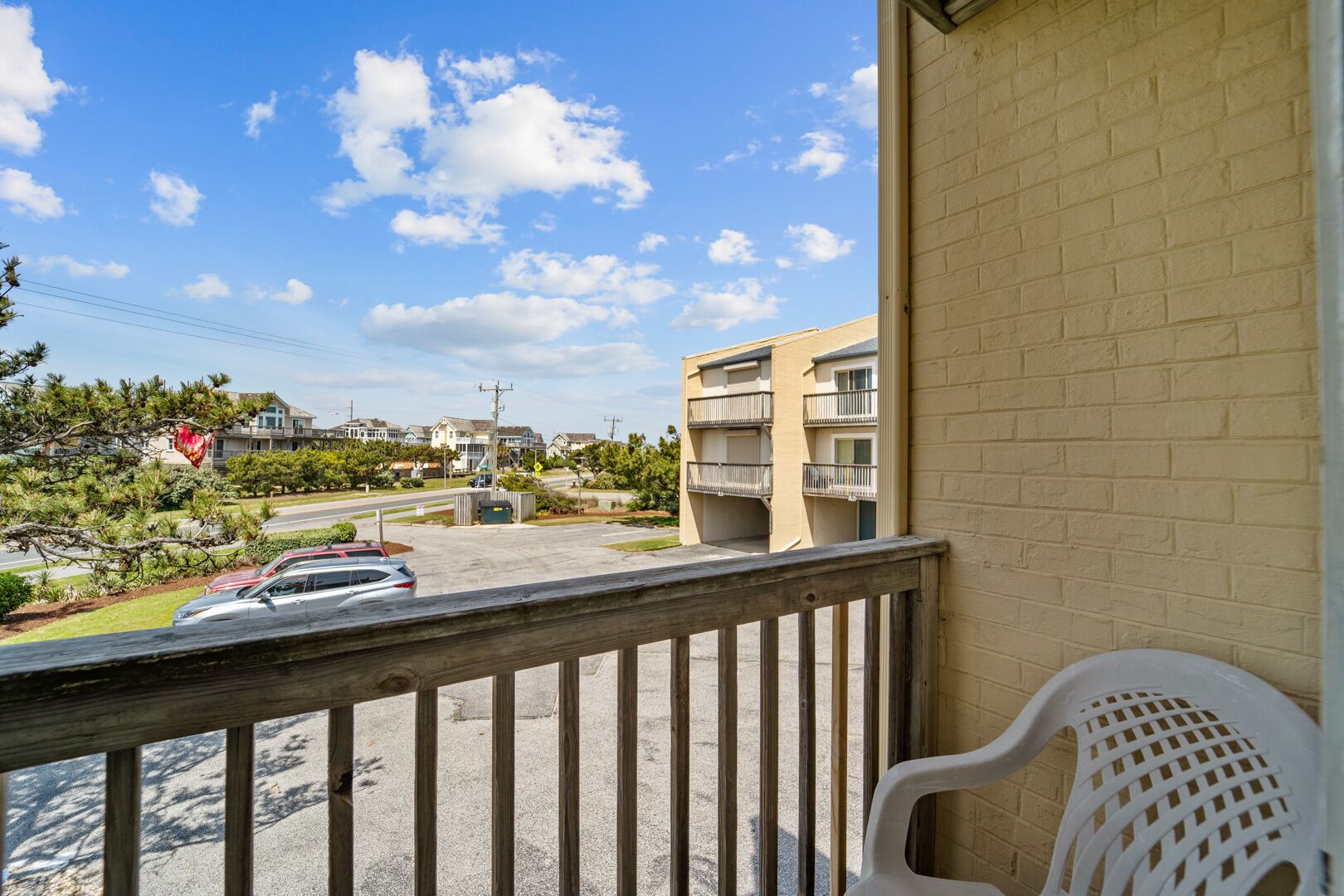 A balcony with a view of a parking lot and a building with multiple floors.