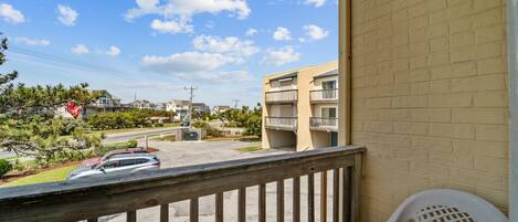 A balcony with a view of a parking lot and a building with multiple floors.