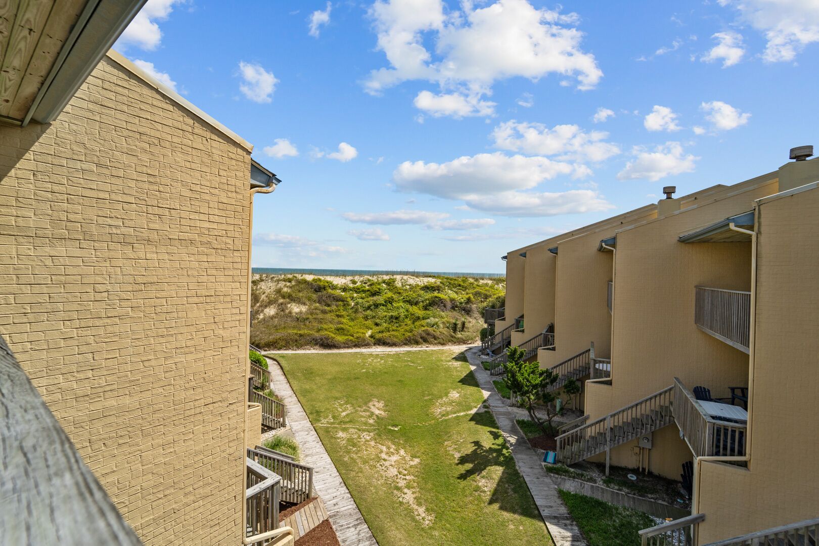 A view of a building with a brick facade and a grassy courtyard.