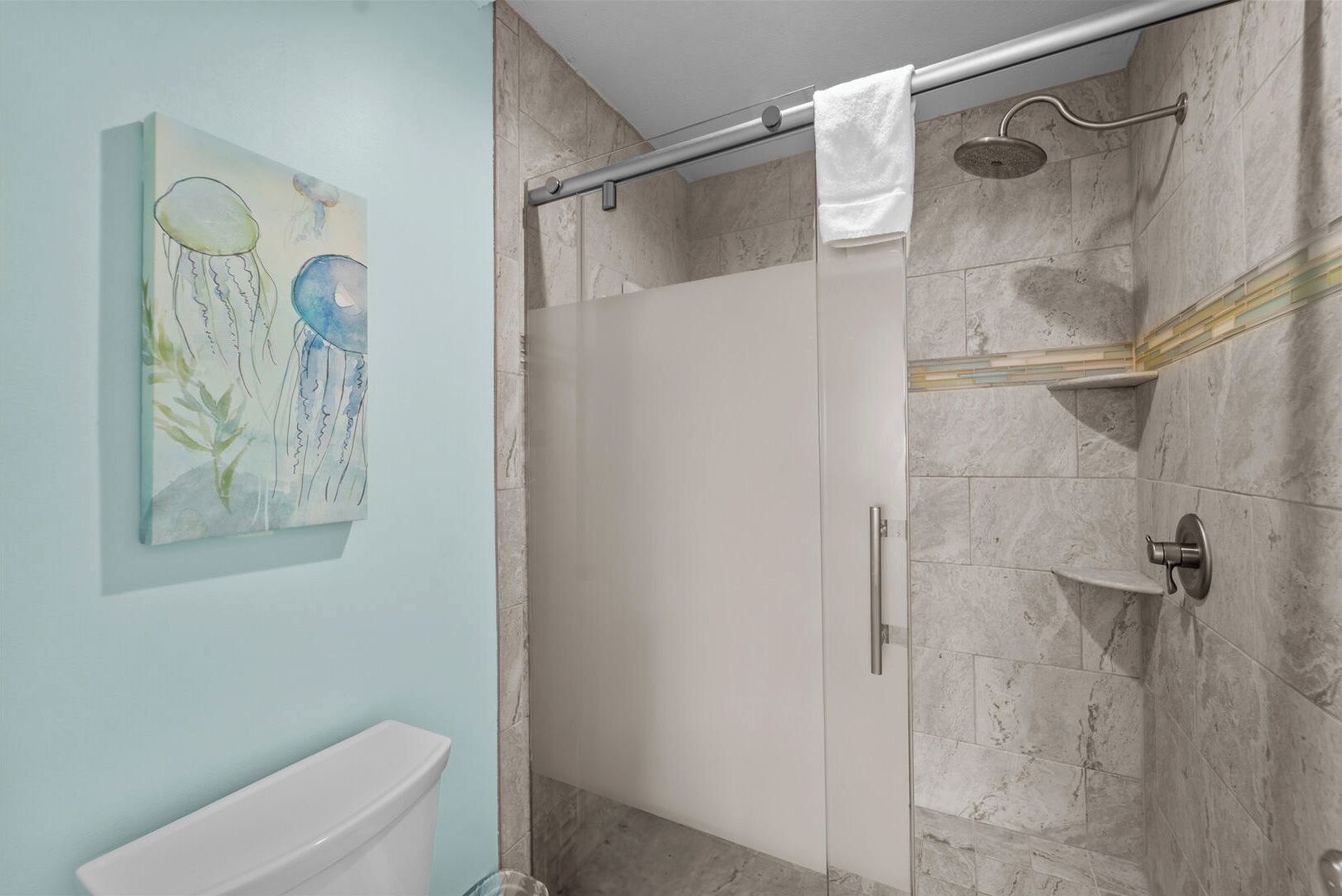 A bathroom with a glass shower enclosure, a toilet, and a wall-mounted sink.